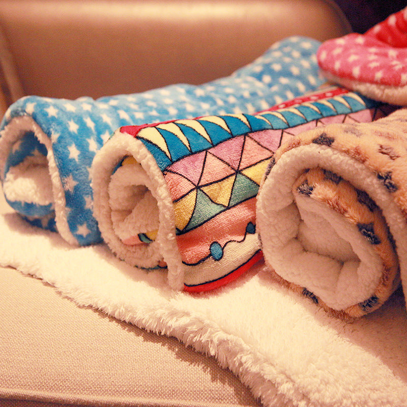 Rolled geometric and pink fleece pet blankets on a bed