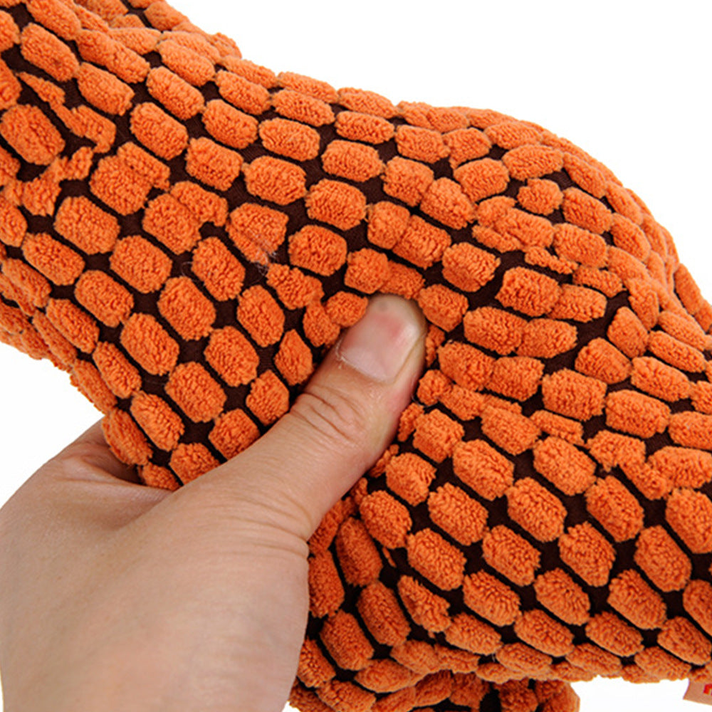Hand squeezing the textured orange plush dinosaur