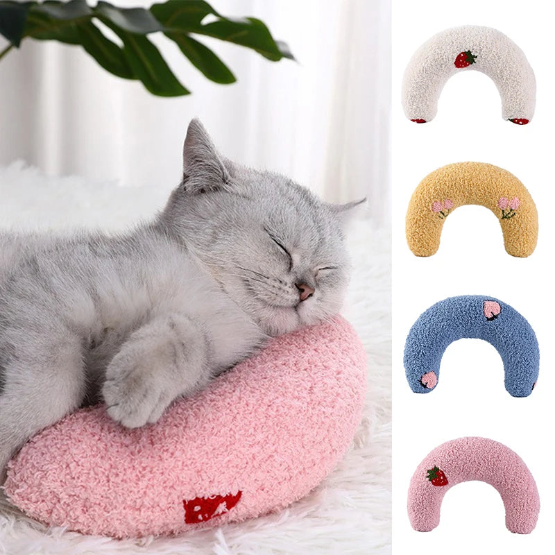 Gray cat resting its head on the pink U-shaped pillow