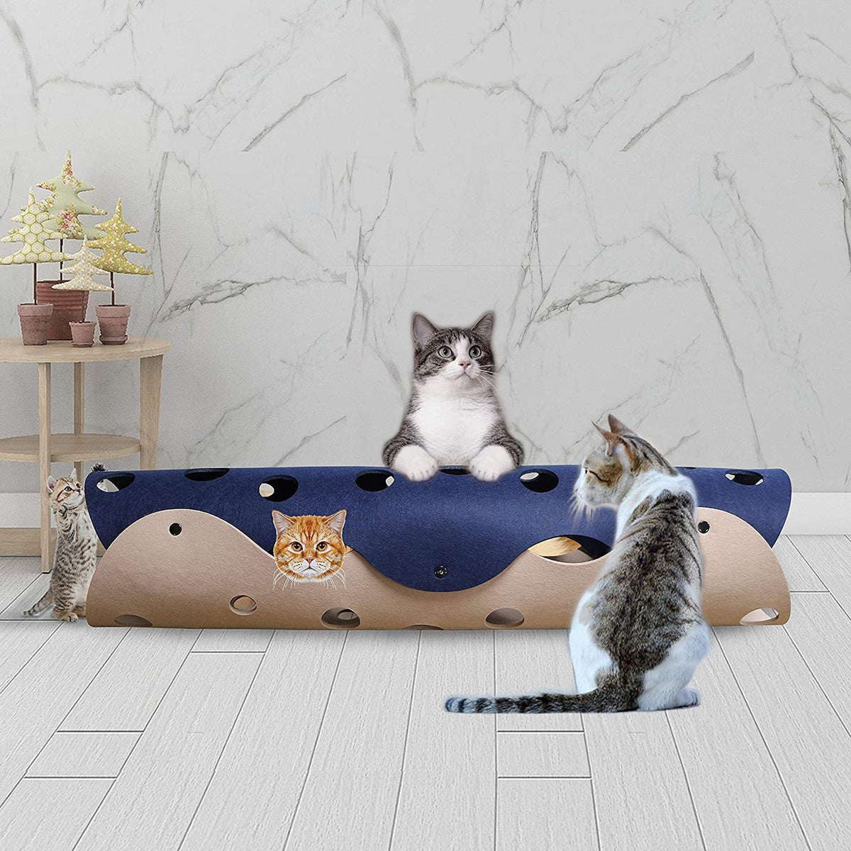 Two cats playing with a navy and beige felt tunnel in a living room